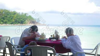 一家有孩子的家庭在海滩上的一家餐馆吃饭。 户外食品